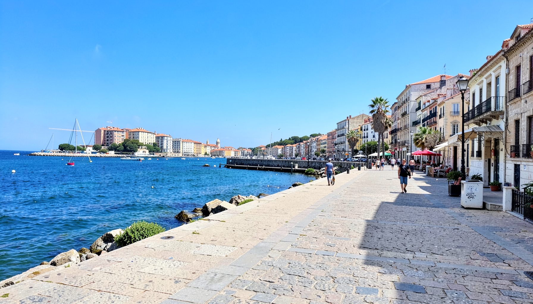 A Mediterranean coastal promenade in Montpellier under a bright blue sky.