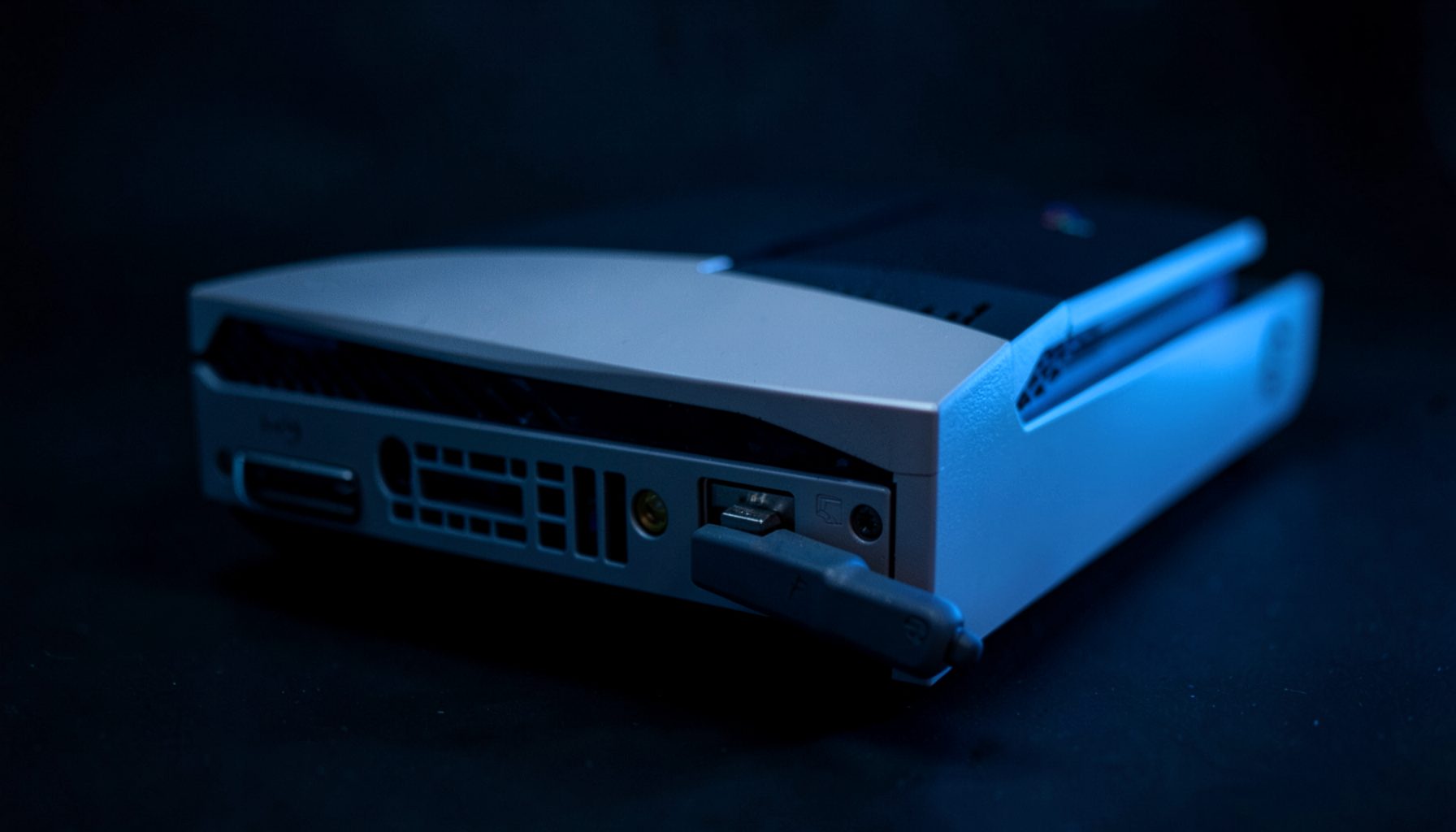 A PlayStation 3 console with a USB dongle plugged into the front port, dark background with subtle blue glow, tech-focused mood