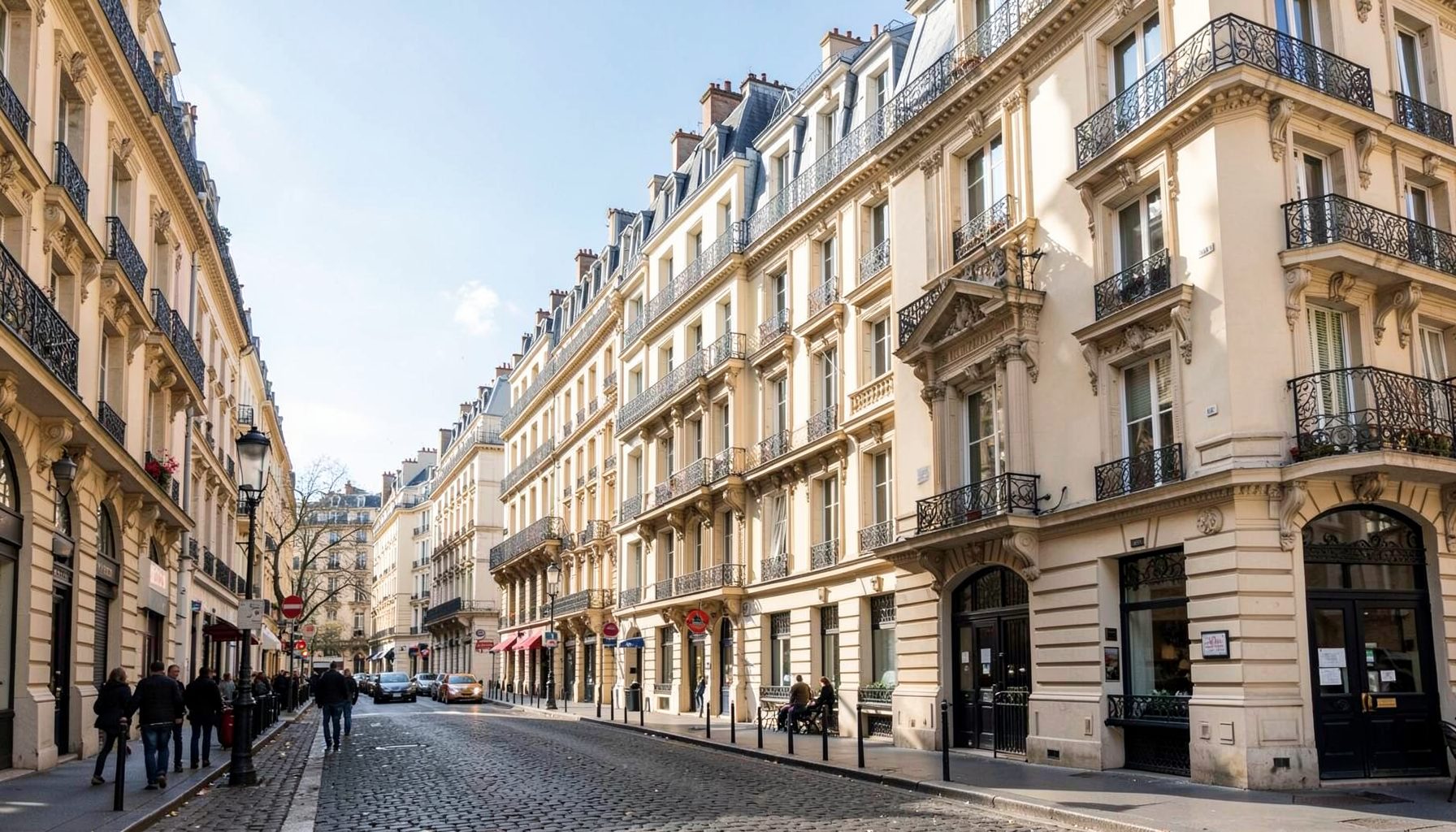 A sunlit Parisian street with classic Haussmann buildings in warm cream and grey tones.