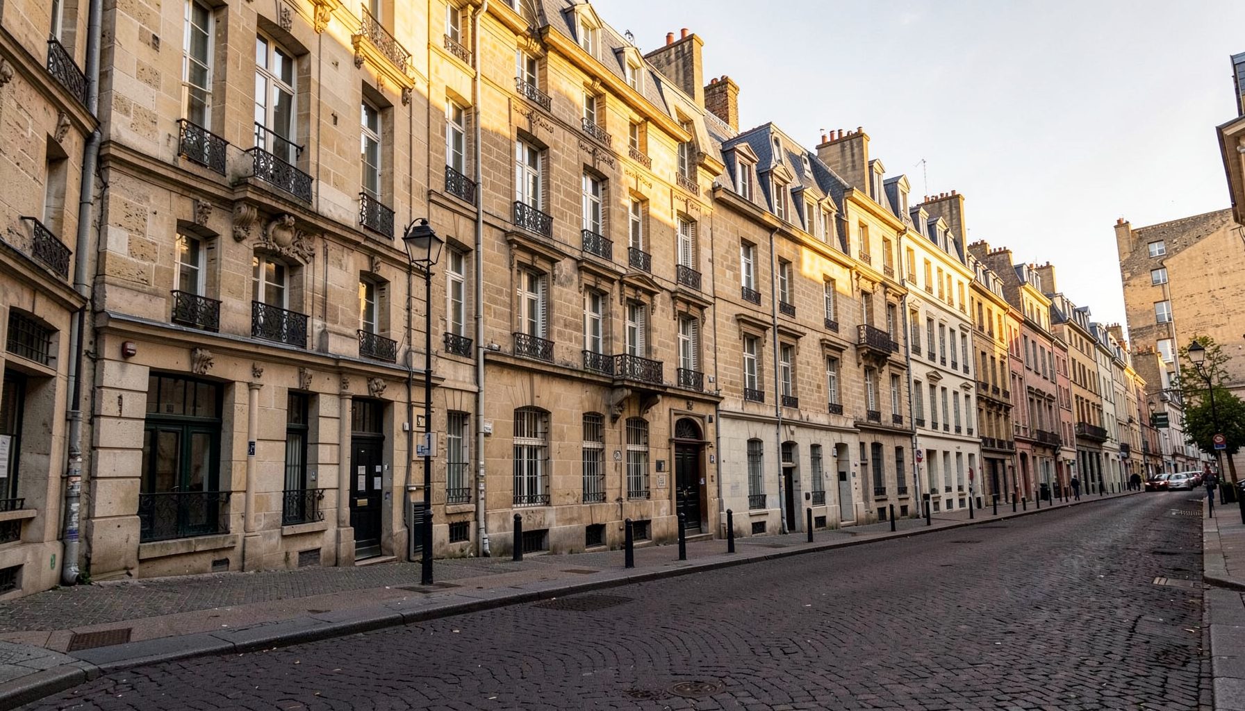 A view of Bordeaux stone facades along a quiet square, golden afternoon light.