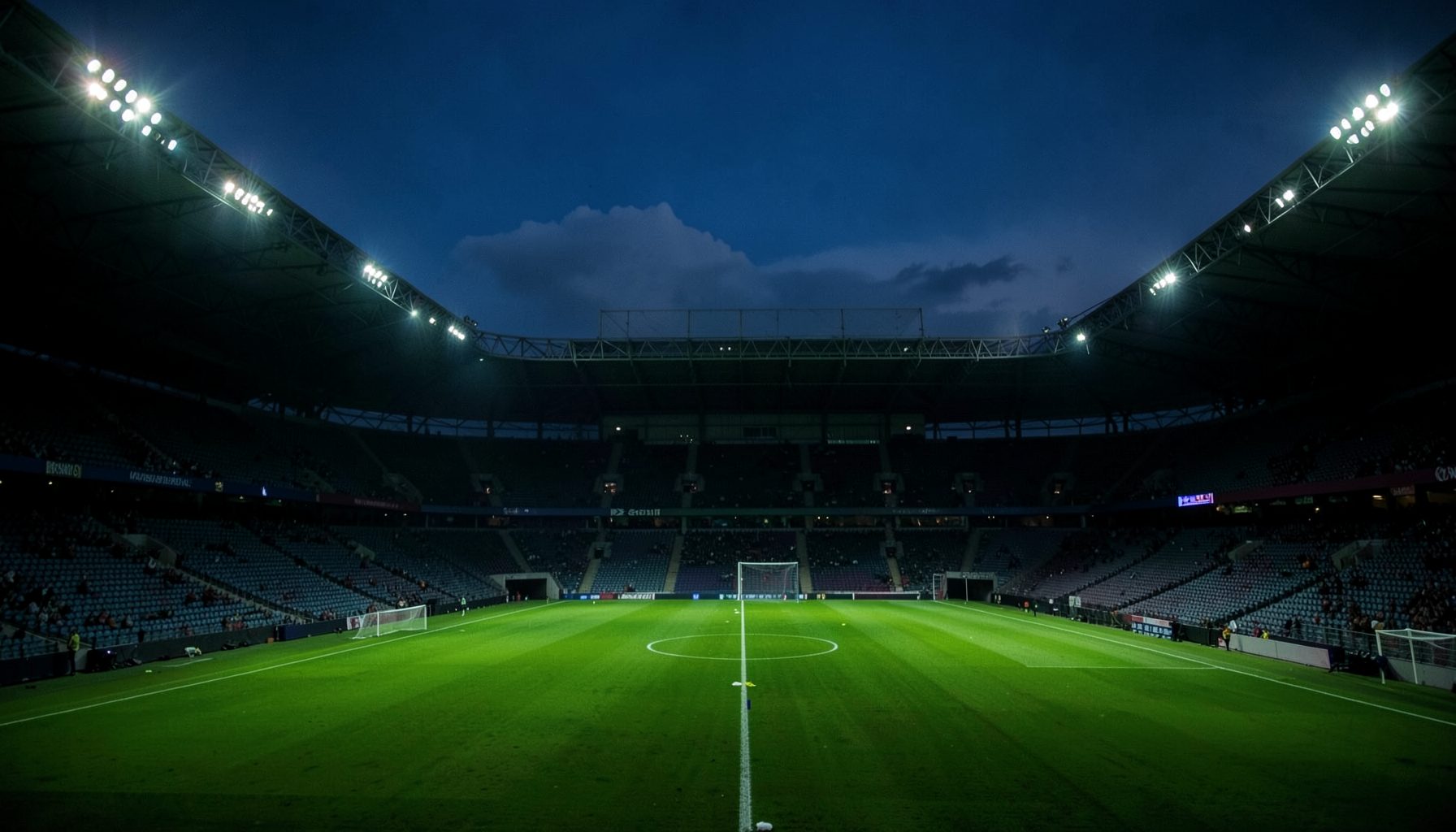 A wide-angle view of a floodlit football stadium at dusk, green pitch glowing under bright lights, empty stands in deep shadow, moody and dramatic atmosphere